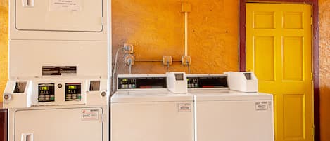 A laundry area with stacked washers and dryers, a yellow door, and visible electrical outlets on the wall.