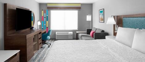 A hotel room with a large bed, a desk with a flat-screen TV, a chair, a desk lamp, and a window with a view.