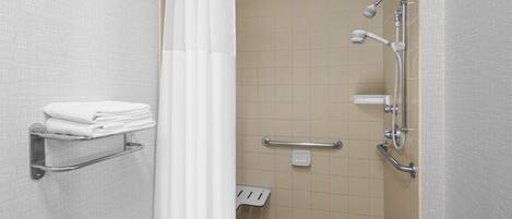 A shower area with a white shower curtain, a grab bar, a towel rack, and a handheld showerhead.