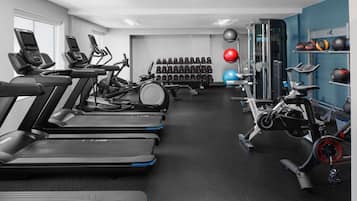 Un gimnasio con cintas de correr, elípticas y equipo de levantamiento de pesas.