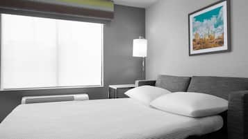 Una habitación de hotel moderna con una cama grande, una mesita de noche, una lámpara y un cuadro en la pared.