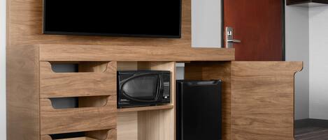 A modern kitchen with built-in appliances, including a microwave and a refrigerator, and a flat-screen TV mounted above the counter.