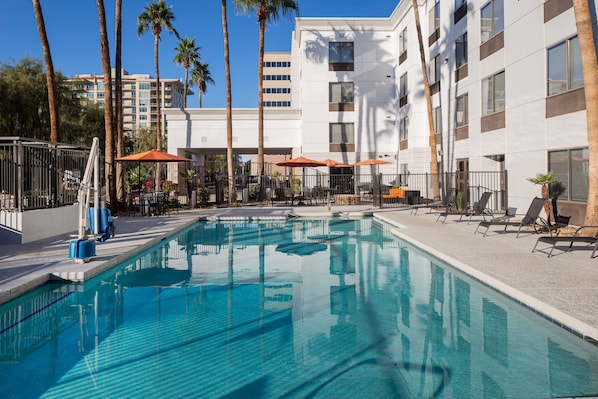 Una piscina al aire libre, sillones reclinables de piscina