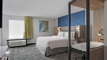 A hotel room with a bed, desk, chair, and a large window with curtains.