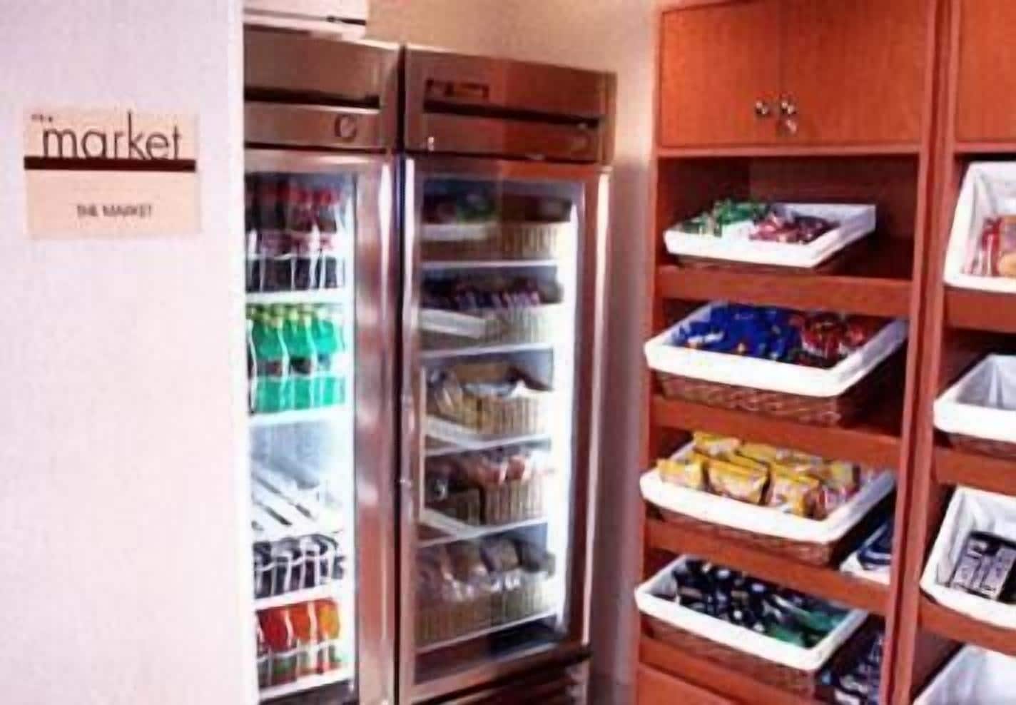 A kitchen with a refrigerator, a freezer, and a wooden pantry with shelves.