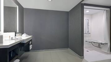 Un baño moderno con un espejo grande, dos lavamanos, una zona de ducha y un perchero para toallas.