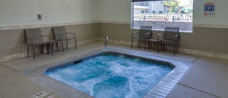 A spa area with a hot tub, seating, and a window with a view.