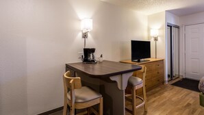 Eine kleine Küchenzeile mit einer Kaffeemaschine, einem Fernseher und einem Holztisch.