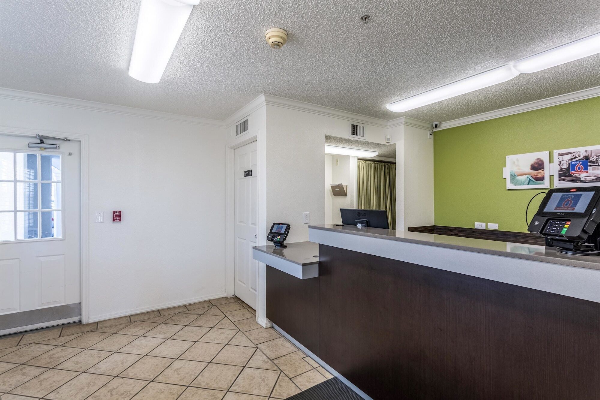 A reception area with a dark reception desk, a computer, and a green wall with pictures.