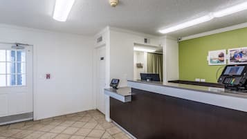 A reception area with a dark reception desk, a computer, and a green wall with pictures.