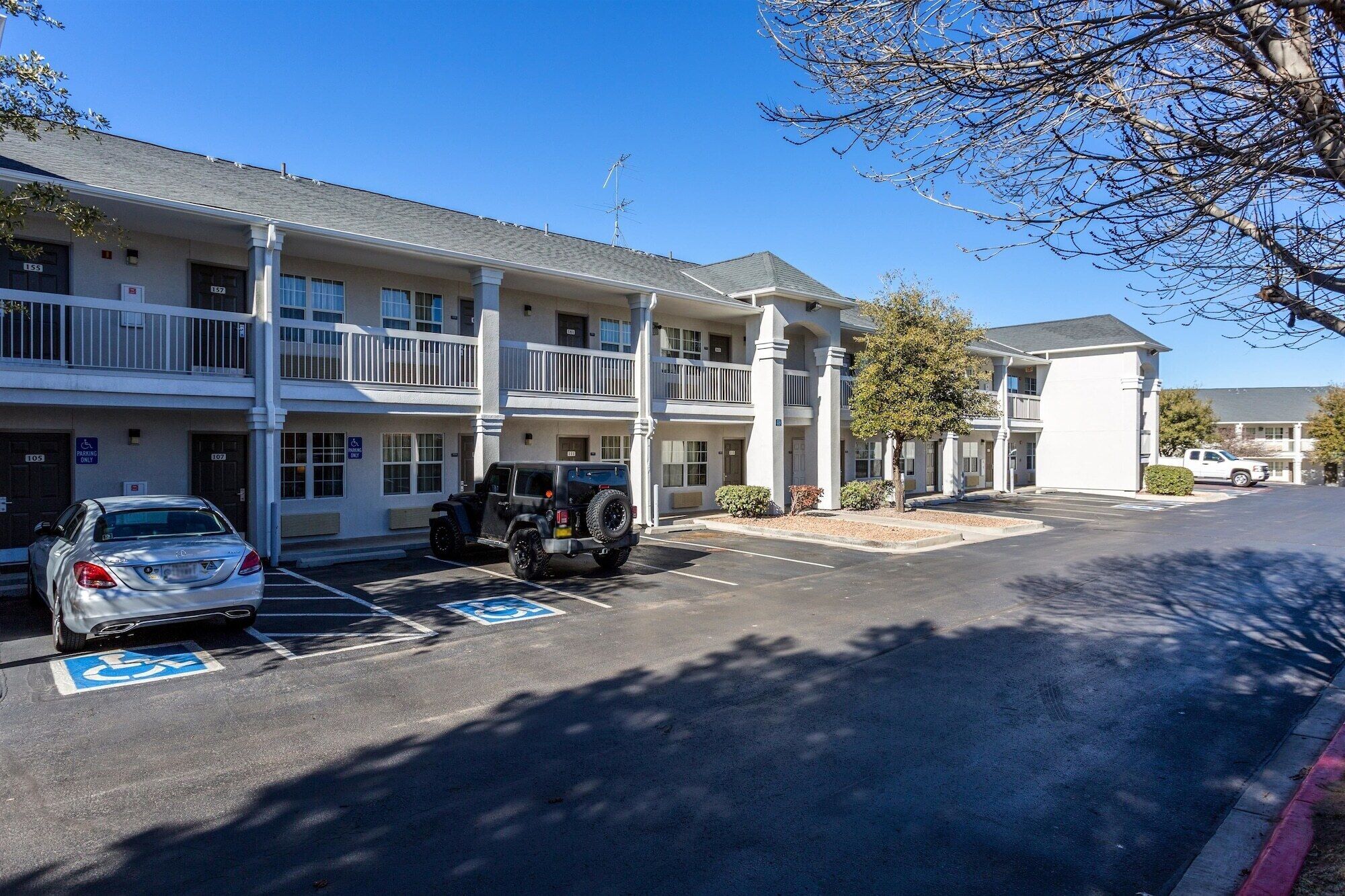 A multi-story hotel with parking spaces, including a handicapped accessible spot.