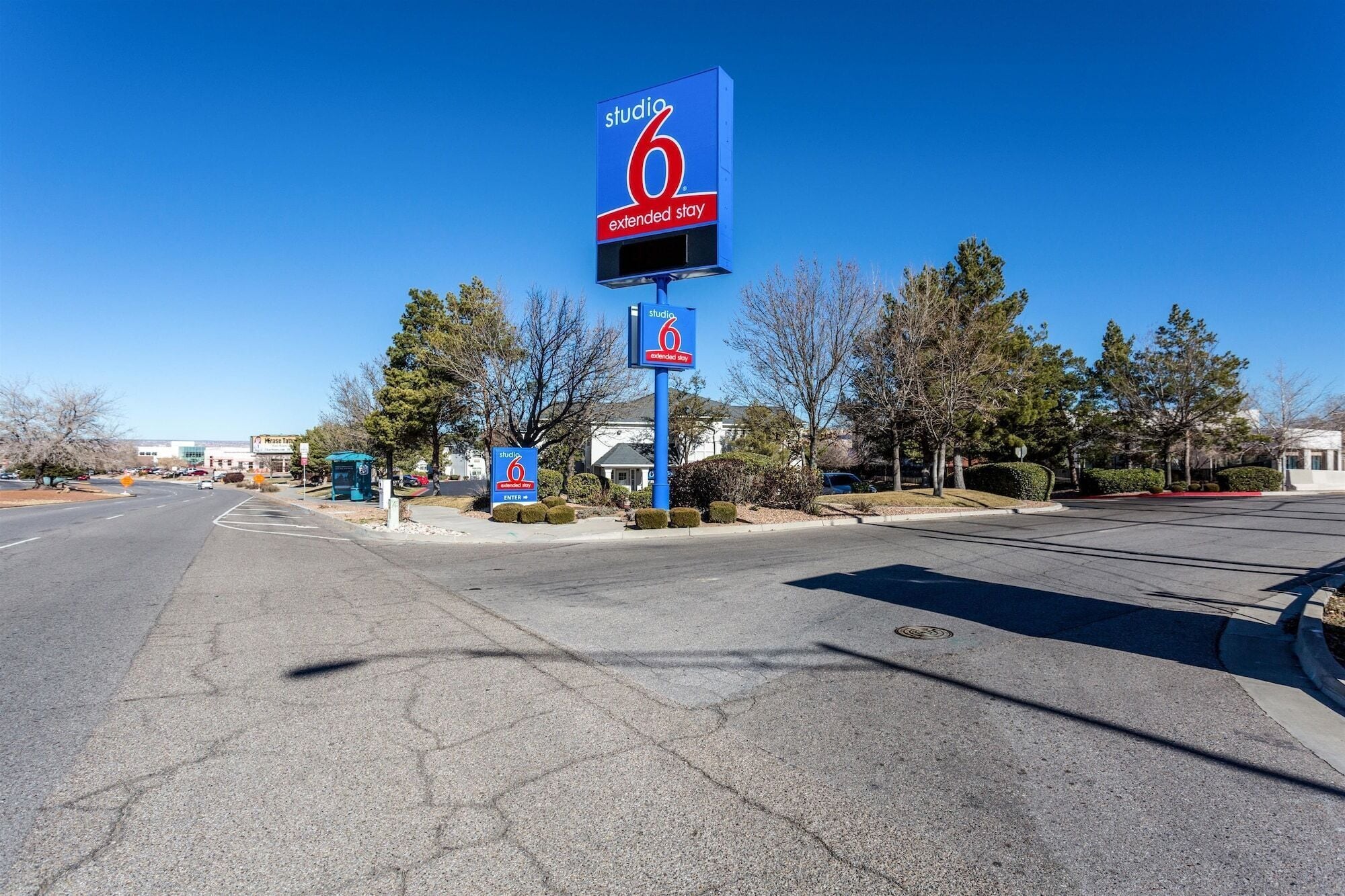 A Studio 6 Extended Stay hotel sign with a clear road and parking area in front.