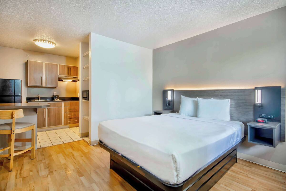 Ein modernes Hotelzimmer mit einem Bett, einem Schreibtisch und einer Küchenzeile.