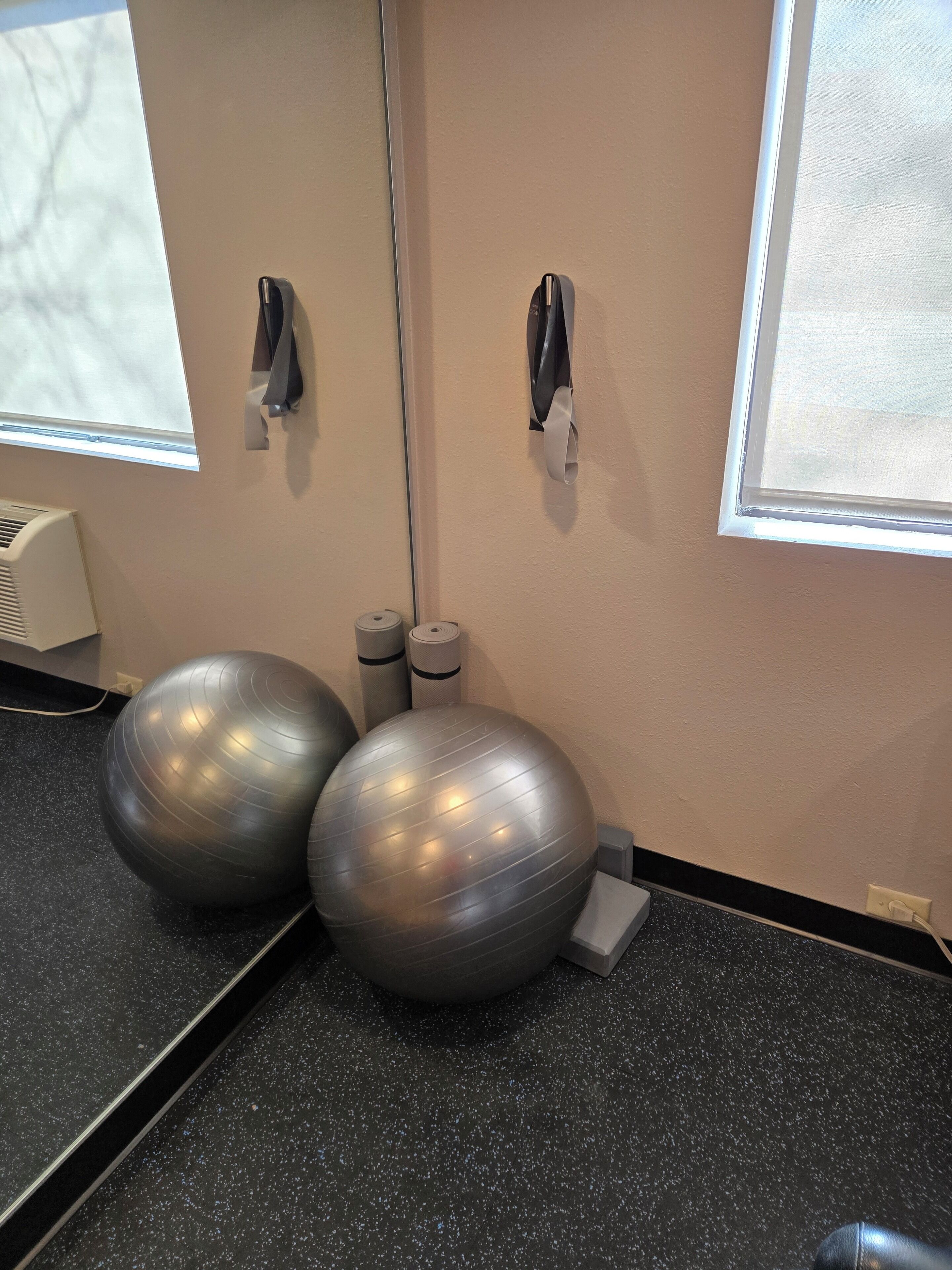 A room with exercise balls, a mirror, and a window.
