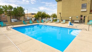 A rectangular pool with clear blue water, surrounded by light blue lounge chairs and a beige tiled deck. - Best Western North I-25 Hotel (Albuquerque)