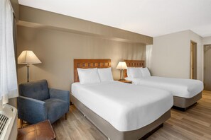 A hotel room with two beds, a chair, a lamp, and a door. - Best Western North I-25 Hotel (Albuquerque)