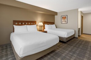 A hotel room with two beds, a nightstand with a lamp, a framed picture on the wall, and a carpeted floor. - Best Western North I-25 Hotel (Albuquerque)