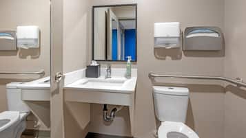 Et standard badeværelse med håndvask, spejl, toilet og håndtørrer.