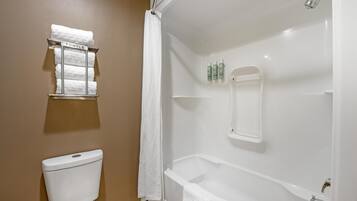 Un baño con inodoro, ducha con puerta de vidrio y toallero con toallas.