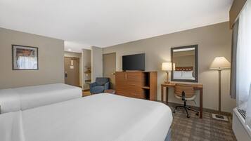 A hotel room with two beds, a desk, a chair, a dresser, a mirror, and a television.