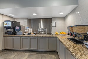 A modern kitchen with a coffee station, a fruit bowl, and a stainless steel sink.