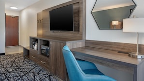 Habitación de hotel con televisor de pantalla plana, espejo, escritorio y silla.