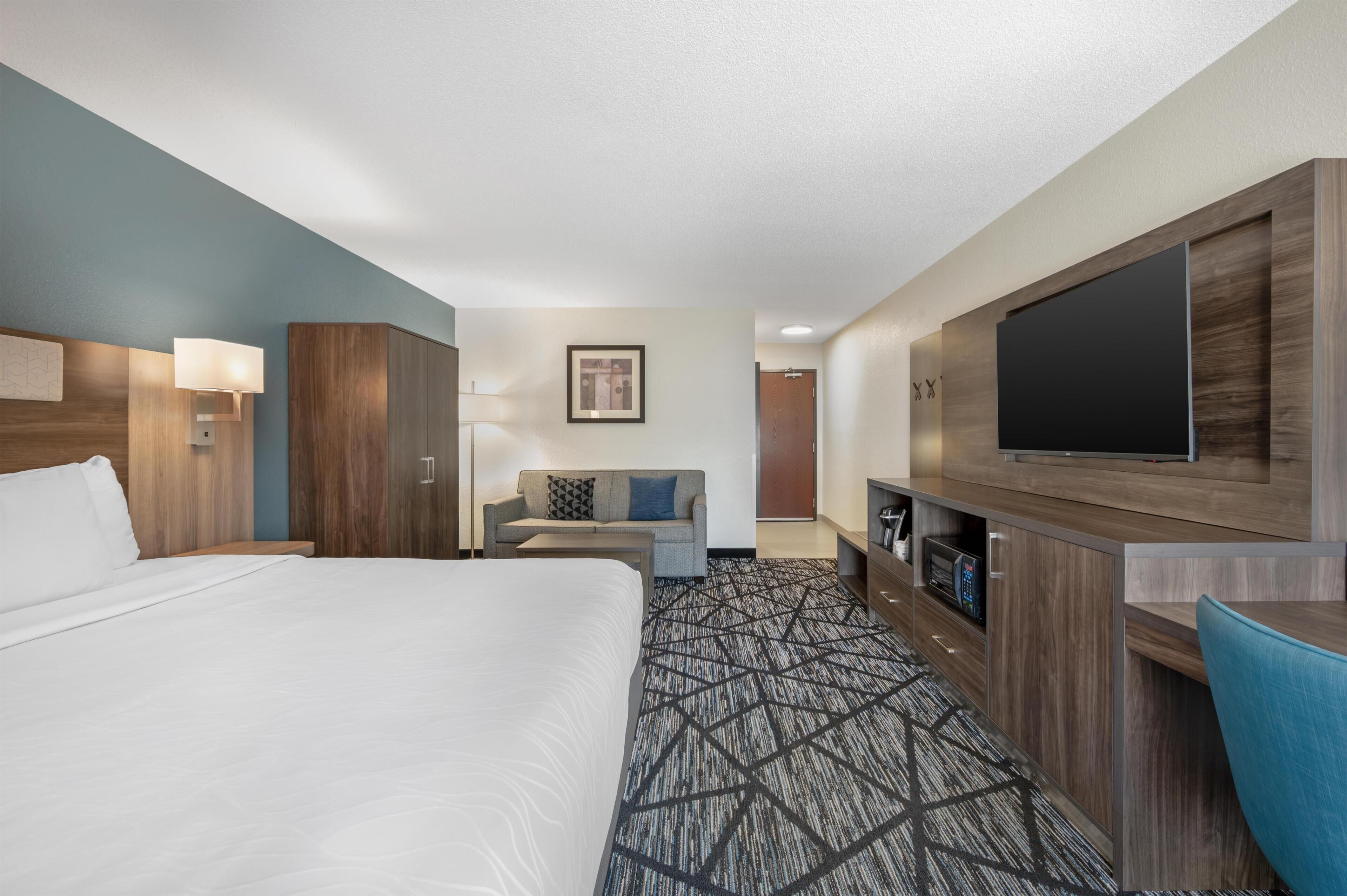 Ein Hotelzimmer mit einem großen Bett, einer Couch, einem Fernseher und einem Schreibtisch.