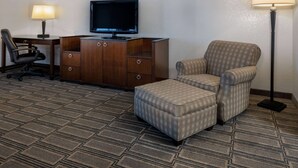 Une chambre d’hôtel équipée d’un bureau, d’une chaise, d’une télévision et d’un repose-pieds.