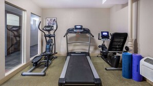 Une salle de remise en forme équipée d’un tapis de course, d’un vélo elliptique et d’un vélo d’appartement.