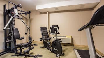 Academia com esteira, bicicleta ergométrica e máquina de pesos.