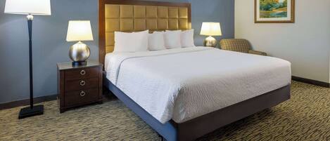 A neatly made bed with white linens, a dark headboard, and two bedside lamps.
