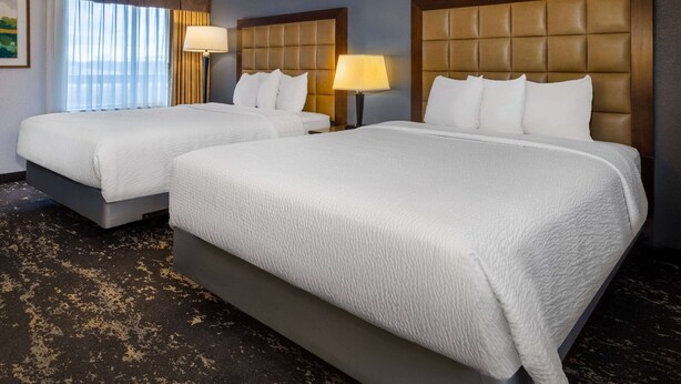 Une chambre d’hôtel avec deux lits, chacun doté d’une tête de lit et d’une lampe de chevet.