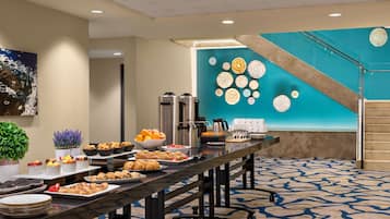 A buffet setup with various food items and a decorative wall with circular patterns.