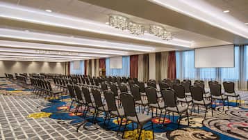 A conference room with rows of chairs, a large carpet with a floral pattern, and a projector screen.