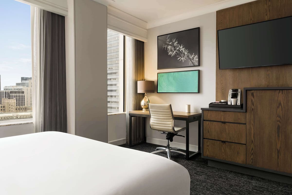 A hotel room with a large bed, a desk with a chair, a television, and a coffee maker.