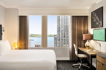 A breakfast table with croissants, fruit, and juice, overlooking a lake with a cityscape in the background. at Hilton Motif Seattle