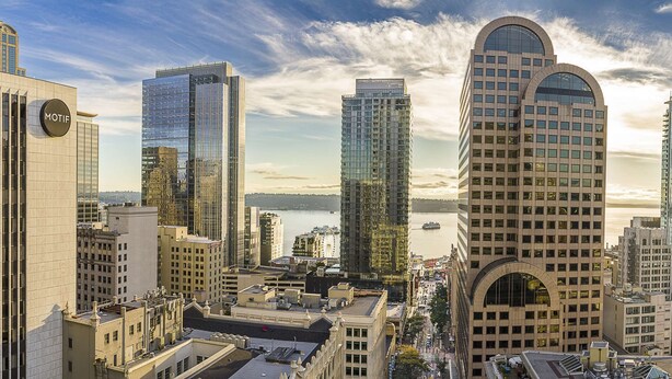 A cityscape with modern high-rise buildings, including a prominent building with a circular sign labeled "MOTIF".