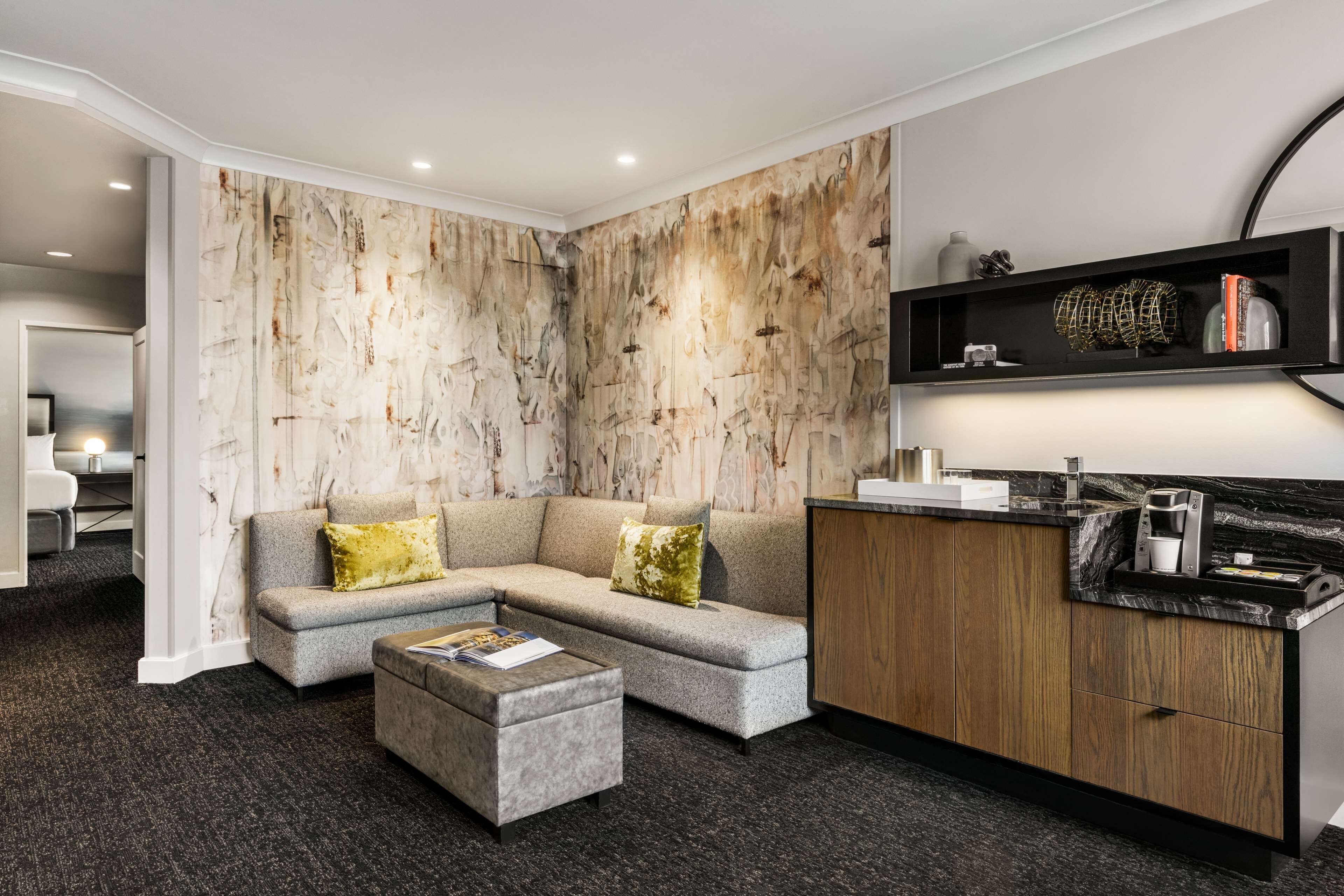 Una sala de estar moderna con un sofá modular gris, un mueble de madera y una encimera de mármol.
