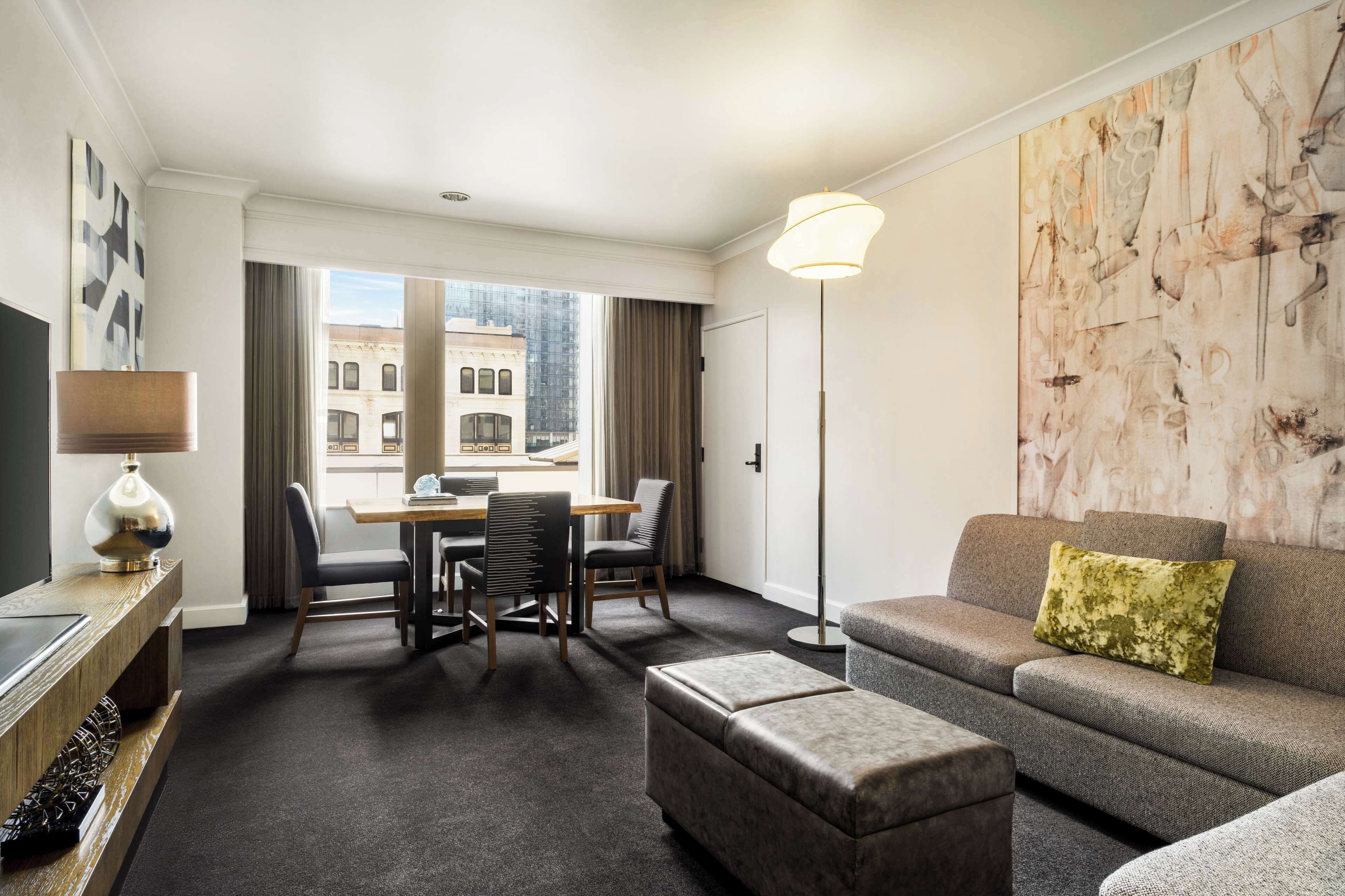 A hotel room with a dining area, a sofa, and a TV.