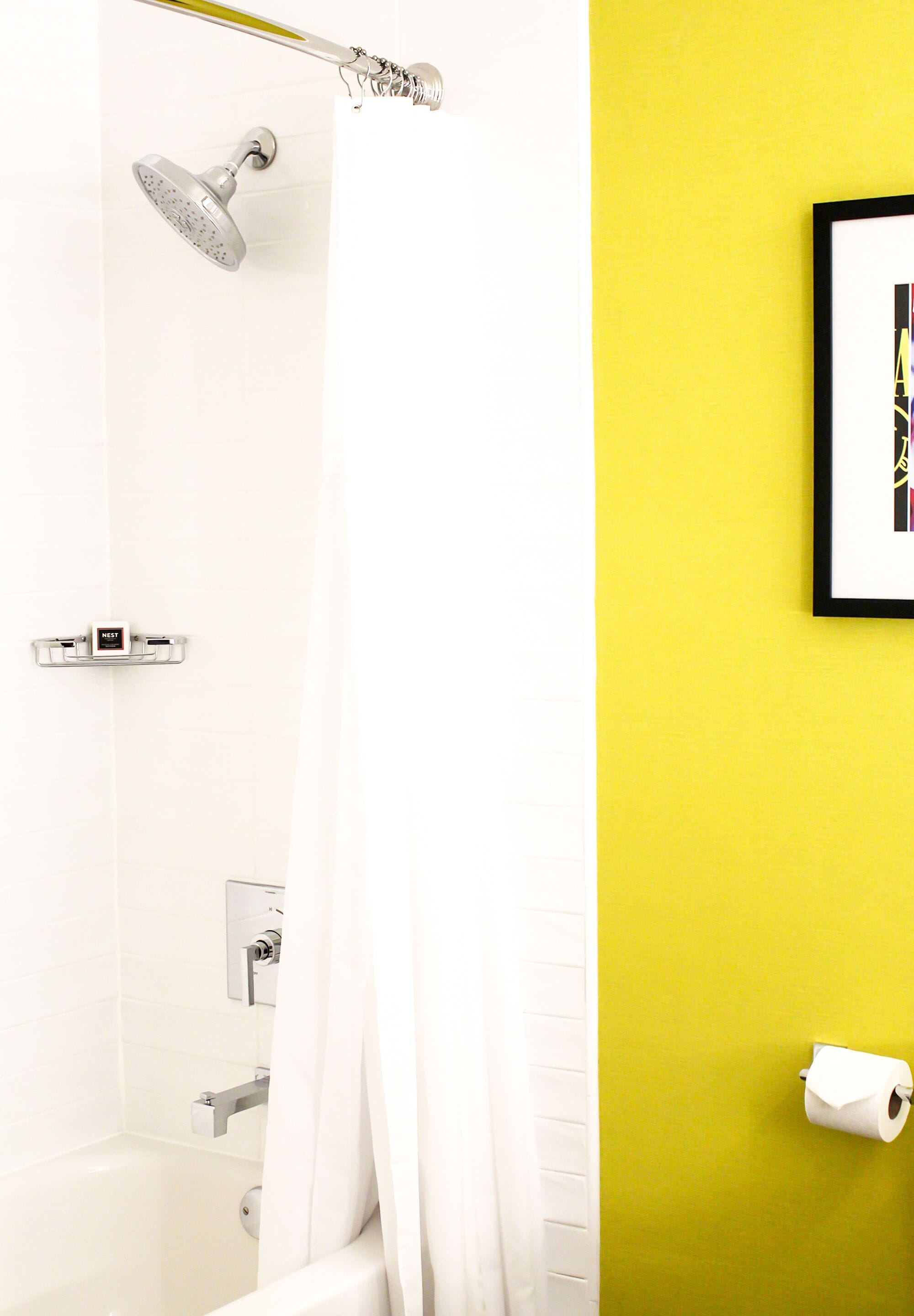 A bathroom with a shower, toilet, and a framed picture on the wall.