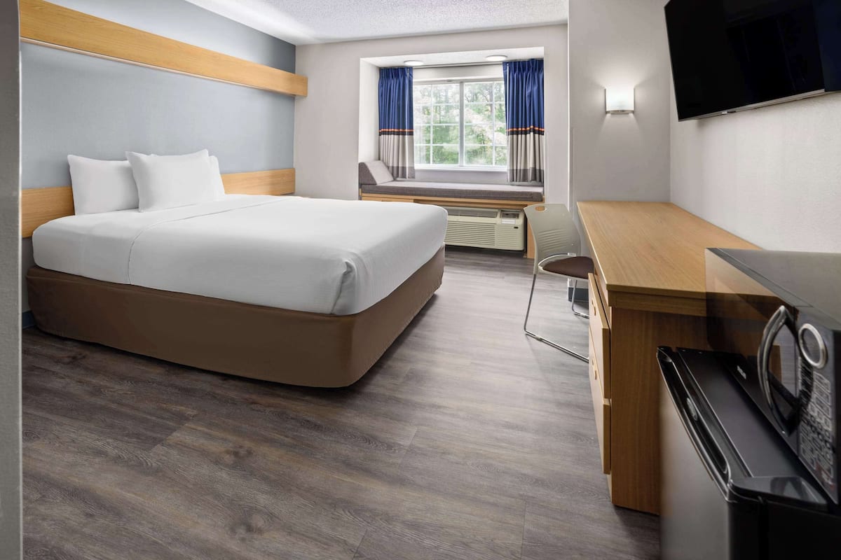 Une chambre d’hôtel équipée d’un lit, d’un bureau, d’un four à micro-ondes et d’une télévision.