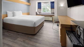 Habitación de hotel con cama, escritorio, microondas y televisión.