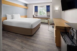 A hotel room with a bed, a desk, a microwave, and a TV. - Microtel Inn by Wyndham Raleigh Durham Airport (Morrisville)