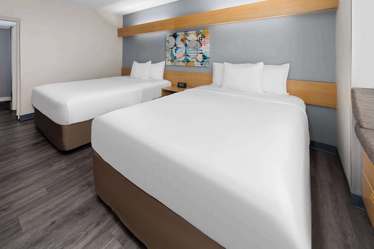Une chambre d’hôtel avec deux lits, une tête de lit en bois et une peinture abstraite aux couleurs vives accrochée au mur.