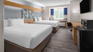 A hotel room with two beds, a desk, a television, and a window with curtains. - Microtel Inn by Wyndham Raleigh Durham Airport (Morrisville)