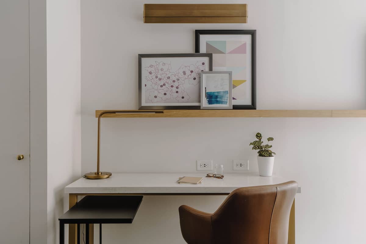 A modern workspace with a desk, chair, and framed artwork on the wall.