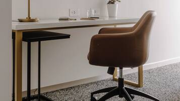 A modern office space with a desk, chair, and framed artwork on the wall.