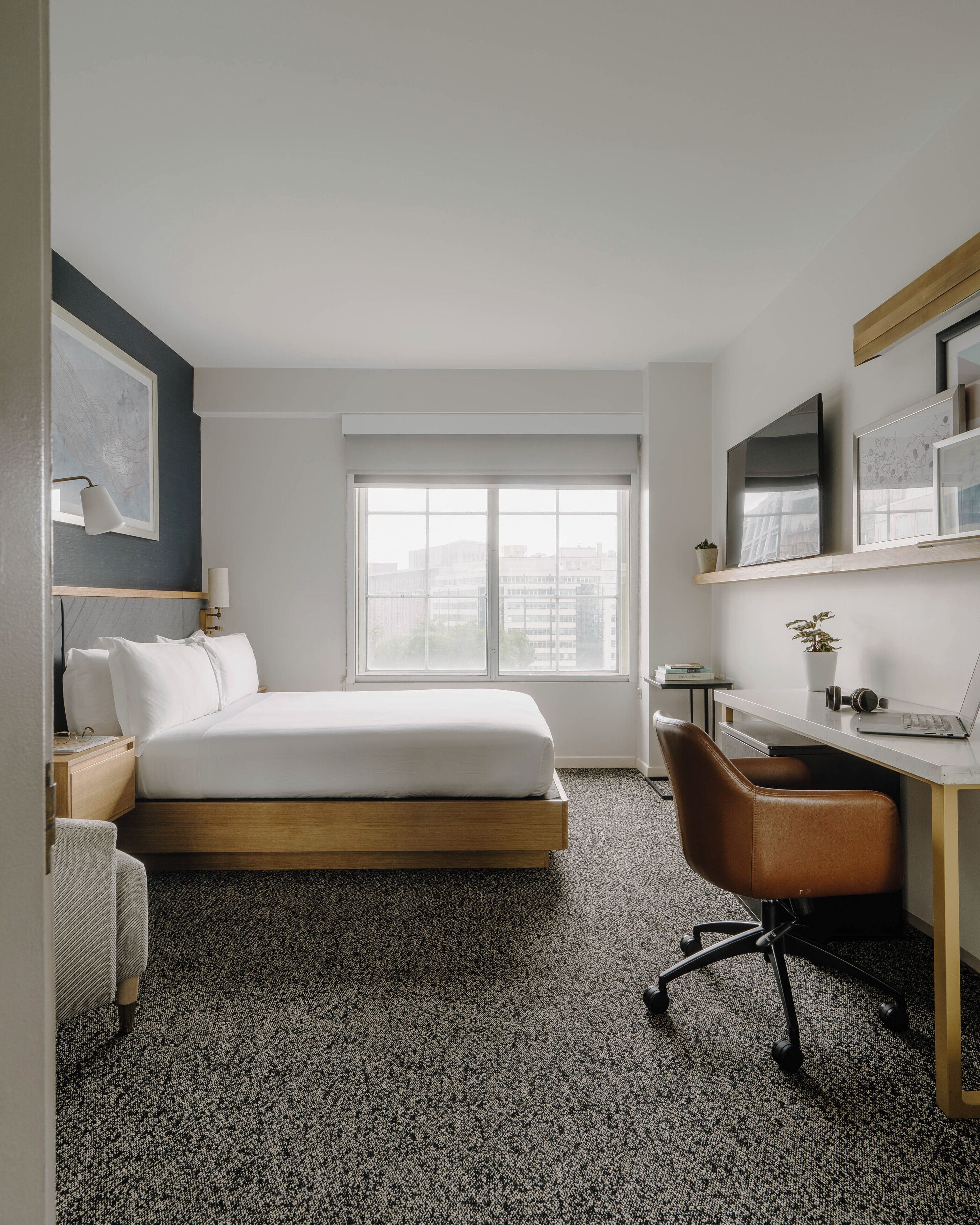 Quarto de hotel moderno com cama, escrivaninha e cadeira.