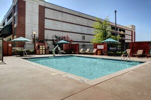 Una piscina al aire libre, sombrillas, sillones reclinables de piscina