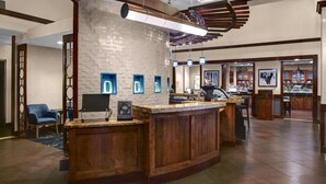 A reception area with a wooden counter, a white brick wall, and a blue chair.